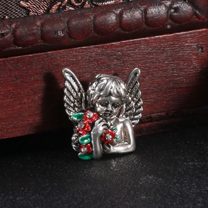 Detailed close-up of retro silver angel brooch holding red flowers with rhinestones