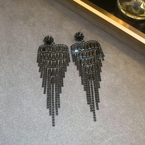 Macro detail of gunmetal flower tassel earrings with shimmering crystals on dark texture