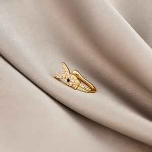 Macro view of gold bunny ear cuff with clear crystals and black eye on silk fabric