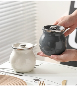 Holding a grey ceramic lard jar with lid and spoon alongside a white seasoning pot