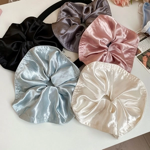 Detailed view of assorted satin scrunchies in black, pink, blue, and cream silk fabric