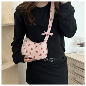 Pink corduroy crescent bag with strawberry print and bow detail worn by model