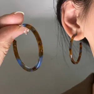 Detail view of large tortoise resin hoop earrings with blue accents and silver hooks