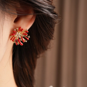 Close-up of elegant red coral-style fireworks earring with diamonds on model's ear