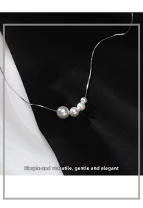 Macro shot of four white pearls in graduated sizes on a delicate silver chain necklace