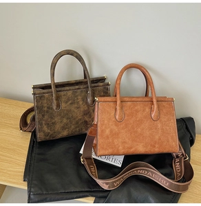 Detail of vintage textured leather bags with round handles and lettered wide straps