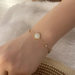 Close-up of gold chain bracelet with hexagonal mother of pearl and crystal accents