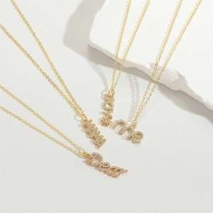 Golden mama and love letter necklaces with rhinestones on a white marble stone base