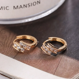 Macro shot of gold hoop earrings set with six brilliant white zircons for women