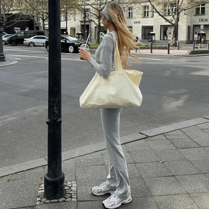 Detail shot of a grey slim-fit top and flared trousers with a canvas tote bag