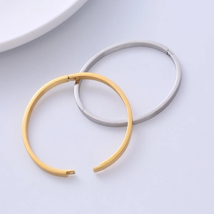 Detail showing polished gold and silver stainless steel hinged bangles on a minimalist background