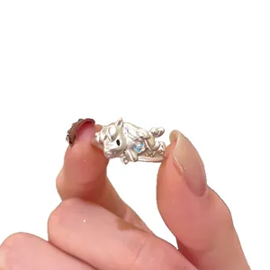 Bague ouverte argentée motif animal avec relief fleur bleue sur fond blanc minimaliste