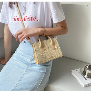 Detail of summer straw bag with floral embroidery worn by a model in casual outfit