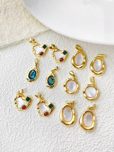 Macro shot of gold-plated heart and oval charms with mother-of-pearl and colorful gemstones
