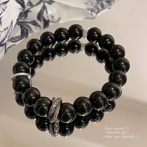 Macro shot of black obsidian bead bracelet with silver spacers reflecting on mirror