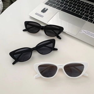 Close-up of retro cat-eye sunglasses with wide frames on a desk with a silver laptop