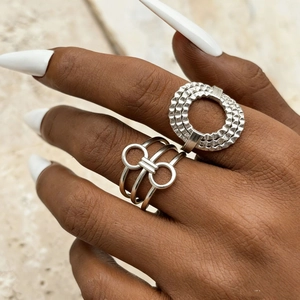 Detailed view of silver irregular geometric rings on hand with textured stone background