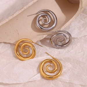 Detailed view of spiral swirl earrings in gold and silver finish on textured background