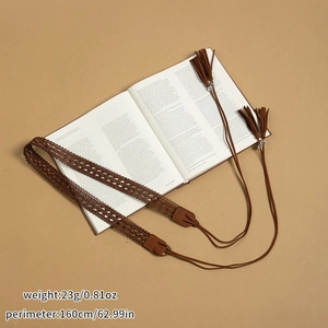 Détail de la ceinture tressée marron faite main avec glands sur un livre vintage