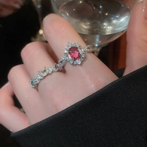 Close-up of elegant oval red zircon ring and silver pavé band on model finger