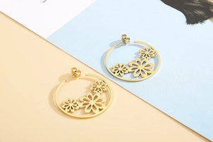 Close-up of golden stainless steel hoop earrings with hollow floral patterns