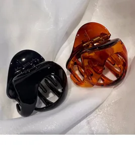 Vue détaillée des grandes pinces à cheveux noires et ambre sur fond de soie blanche