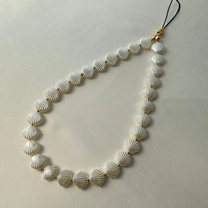 Detailed view of pearlescent shell beads and gold spacers on a stylish phone charm