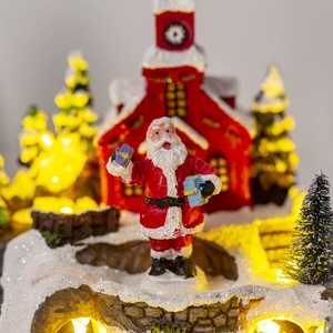 Close-up of LED glowing Christmas house with Santa Claus figurine and warm winter lights