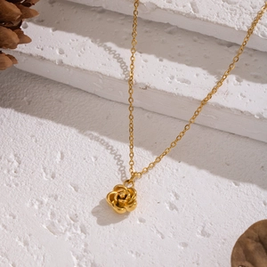 Elegant gold rose flower pendant necklace with fine link chain on a stone base