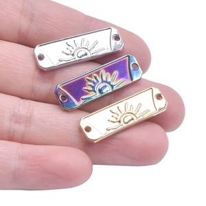 Macro view of three sunburst rectangular jewelry connectors in silver, gold, and rainbow finish