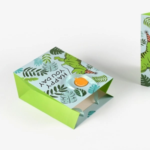 Cute green dinosaur paper gift bag with happy you day text and blue ribbon handles
