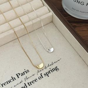 Detail of silver and gold bean pendants on elegant beige jewelry tray with perfume bottle