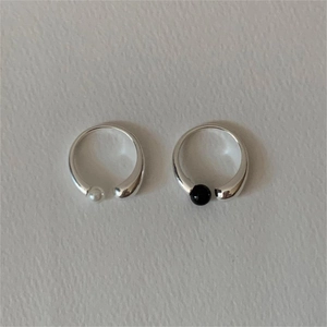 Detail of silver 925 adjustable rings featuring black and white pearls on textured background