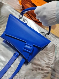 Detail view of cobalt blue asymmetrical leather handbag with a large tonal buckle