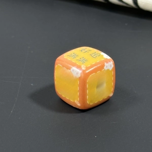 Macro shot of orange acrylic bead with Good Luck Chinese characters and flower patterns