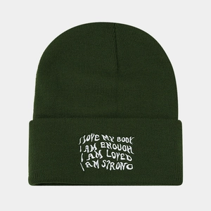 Detailed close-up of dark green ribbed knit beanie featuring white embroidered text