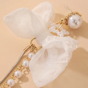 Gros plan sur les boucles d'oreilles en dentelle blanche avec perles et chaînes dorées
