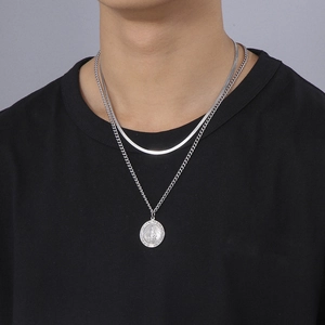 Close-up of layered silver snake chain and Cuban necklace with Virgin Mary medal pendant