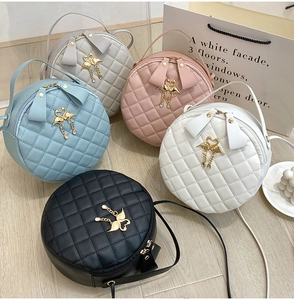 Detail view of round quilted handbags with swan logo and heart tassels in five colors