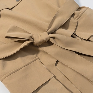 Détail de la ceinture à nœud papillon et du bouton pression du trench-coat kaki