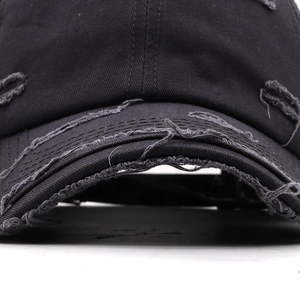 Close-up of distressed black cotton twill baseball cap with frayed edges and vintage details