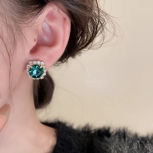 Détail de la boucle d'oreille gemme verte avec halo de cristaux sur monture dorée