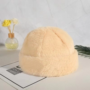 Close-up of soft beige plush beanie cap with a fuzzy texture on a decorative table