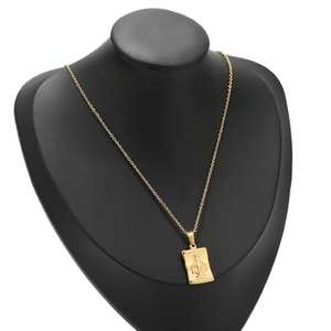 Detail view of a gold rectangular Virgin Mary pendant on a chain on a jewelry display