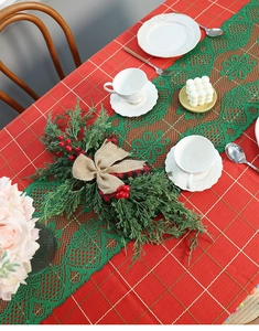 Close-up of green lace Christmas table runner with festive pine needle centerpiece