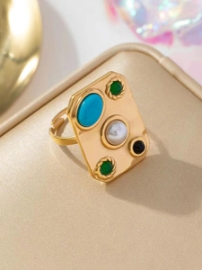 Gros plan d'une bague rectangulaire dorée ornée de turquoise, perle et pierres colorées