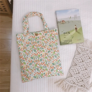 Détail du sac cabas en toile fleurie avec bouton métallique rétro et poignée en tissu robuste