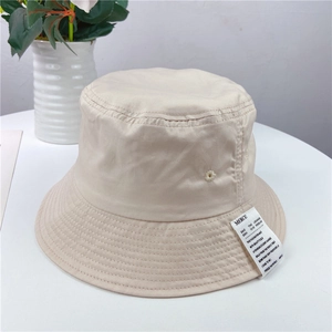 Detailed view of beige fisherman hat featuring a black rectangular textile label and stitching