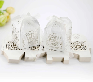 Detail of laser-cut white heart favor box with white ribbon and flat packaging sheets