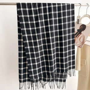 Vertical view of black and white plaid scarf with fringe hanging on a neat hanger